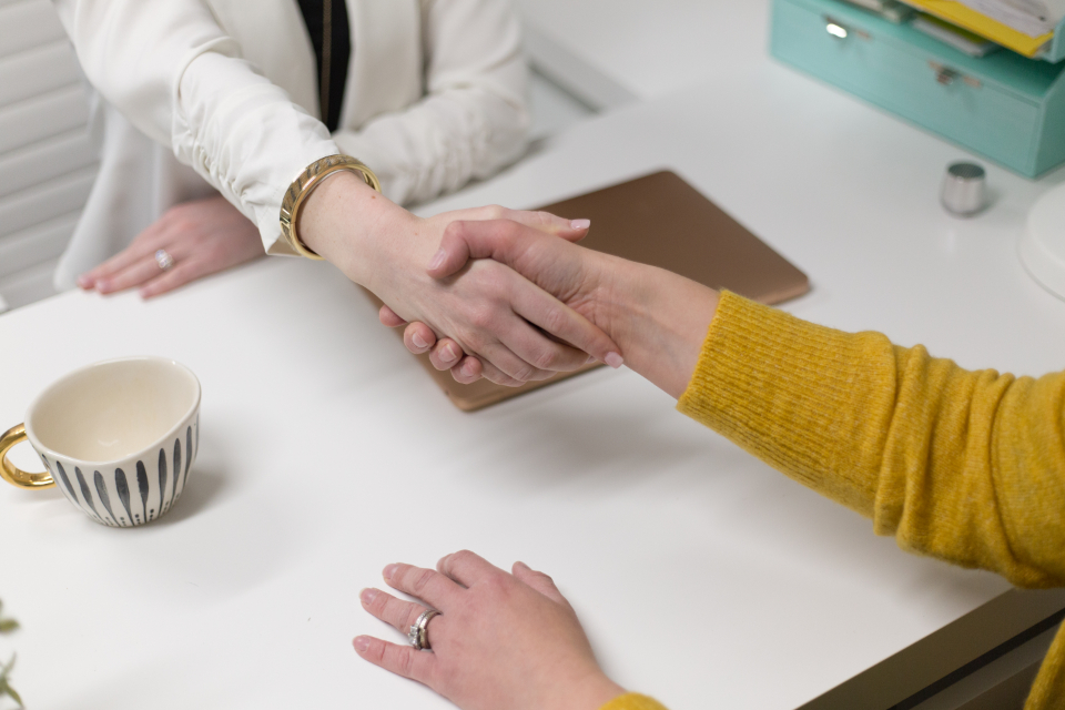 Aperto de mãos entre duas pessoas sobre uma mesa, fechando um acordo