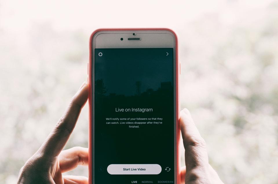 Mãos segurando um celular na vertical com a tela do Instagram aberta