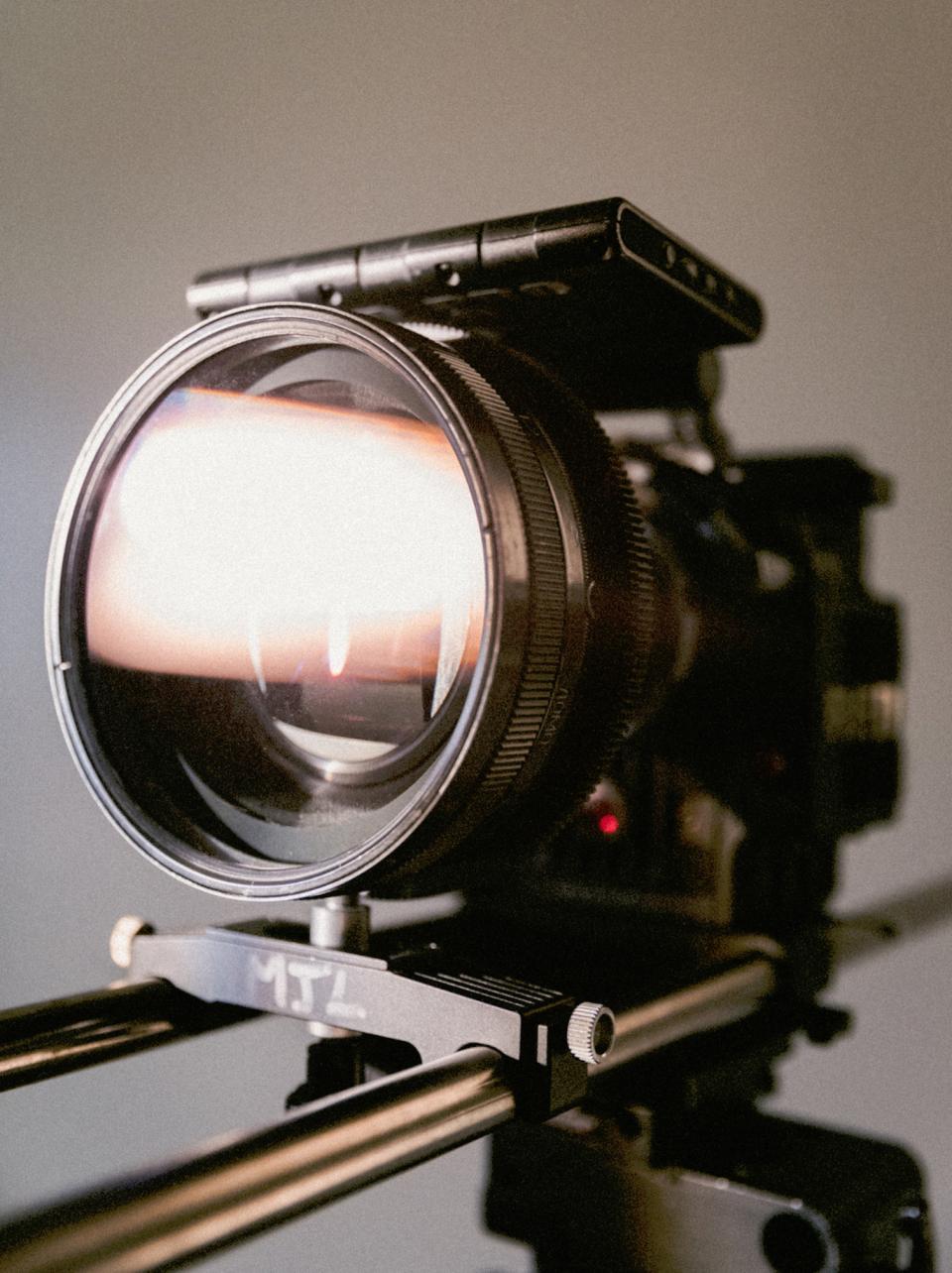 Lente de câmera de cinema montada num slider, refletindo uma luz alaranjada